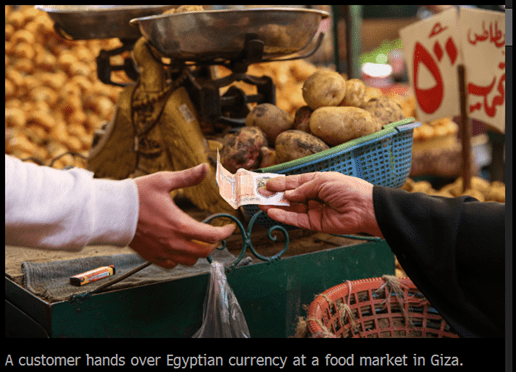 A customer hands over Egyptian currency at a food market in Giza